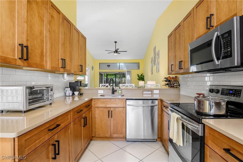 kitchen with ceiling fan, sink, kitchen peninsula, light tile patterned flooring, and appliances with stainless steel finishes