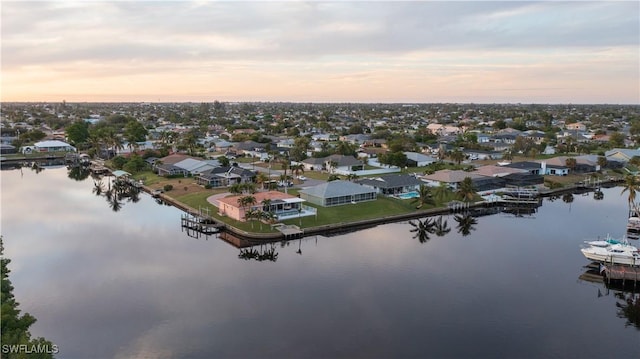 aerial view at dusk featuring a water view