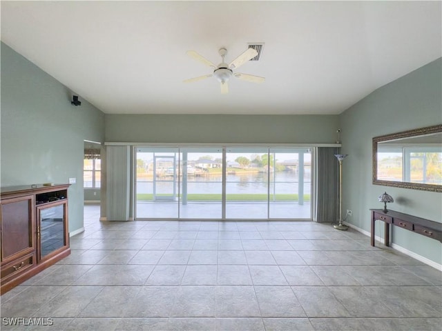 unfurnished living room with a wealth of natural light, a water view, light tile patterned floors, and ceiling fan