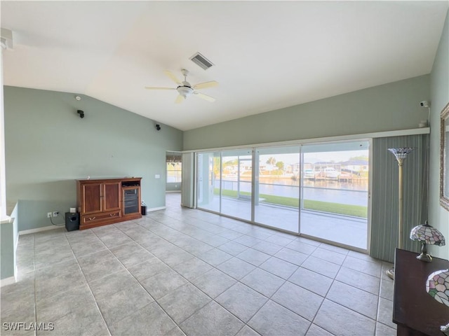 unfurnished living room featuring lofted ceiling, ceiling fan, a water view, and light tile patterned floors