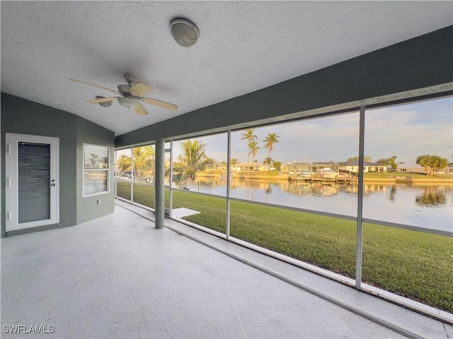 unfurnished sunroom with ceiling fan, a water view, and lofted ceiling