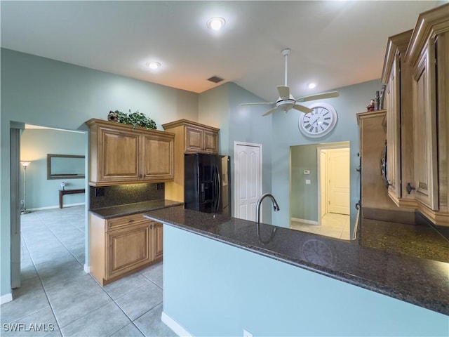 kitchen featuring ceiling fan, sink, dark stone counters, black fridge with ice dispenser, and light tile patterned floors