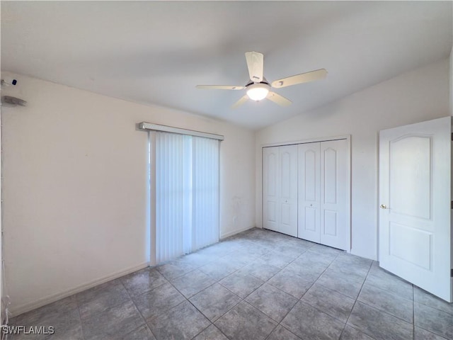 unfurnished bedroom with tile patterned floors, a closet, vaulted ceiling, and ceiling fan