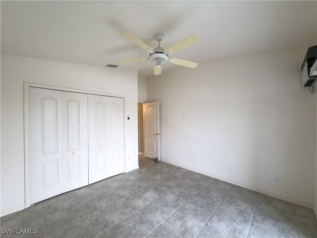 unfurnished bedroom featuring ceiling fan, a closet, and dark tile patterned flooring