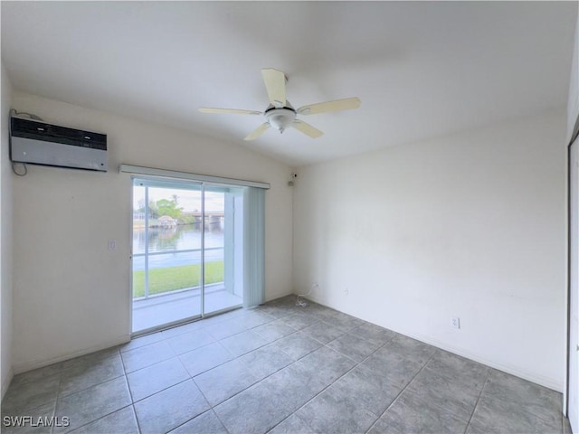 spare room featuring ceiling fan, a wall mounted AC, lofted ceiling, a water view, and light tile patterned floors