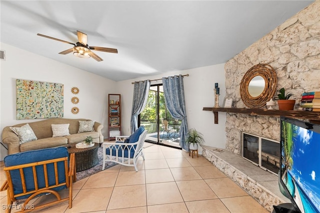 tiled living room featuring ceiling fan, a fireplace, and lofted ceiling