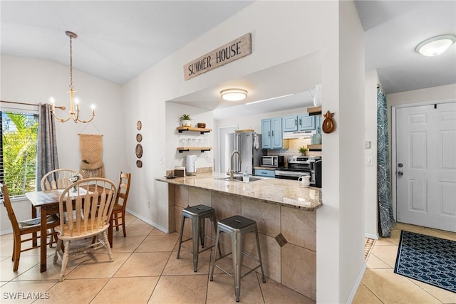 kitchen with blue cabinetry, kitchen peninsula, lofted ceiling, a breakfast bar, and appliances with stainless steel finishes