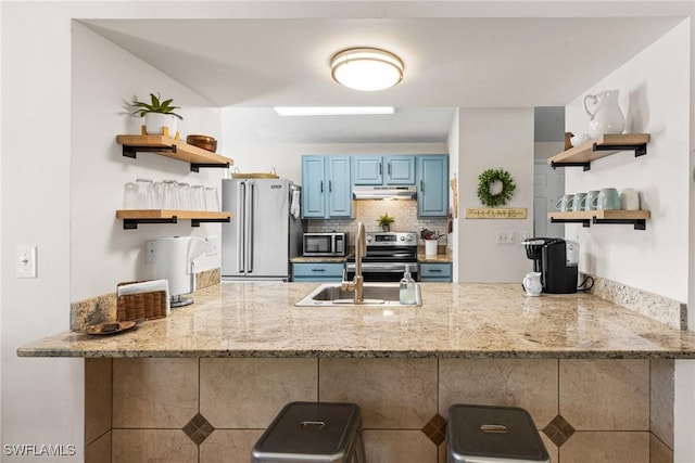 kitchen with blue cabinetry, kitchen peninsula, stainless steel appliances, and light stone counters