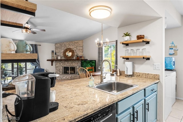 kitchen with sink, a stone fireplace, blue cabinets, light tile patterned floors, and ceiling fan with notable chandelier