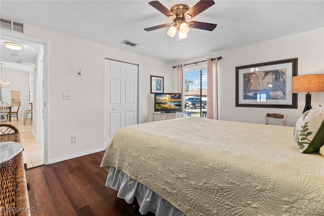 bedroom with ceiling fan with notable chandelier, dark hardwood / wood-style floors, and a closet