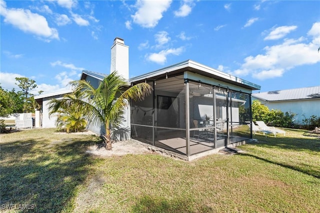 rear view of property with a lawn and a sunroom