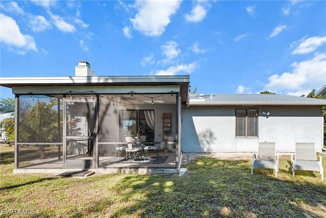 back of property with a sunroom and a yard