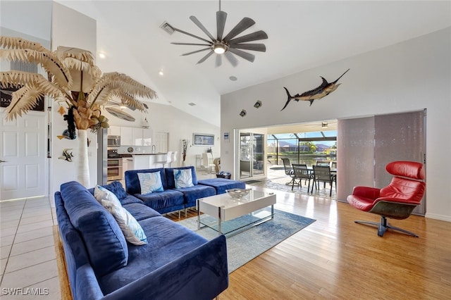 living room with ceiling fan, high vaulted ceiling, and light wood-type flooring