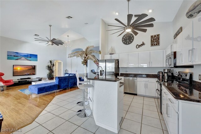 kitchen featuring stainless steel appliances, a kitchen island, white cabinets, and ceiling fan