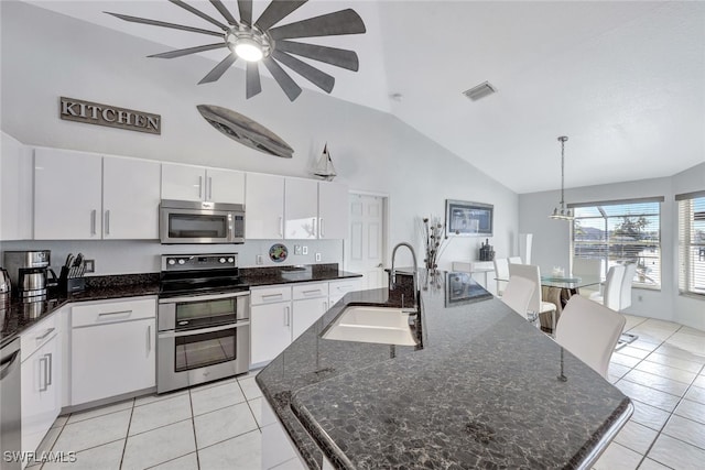 kitchen with decorative light fixtures, an island with sink, sink, white cabinets, and stainless steel appliances