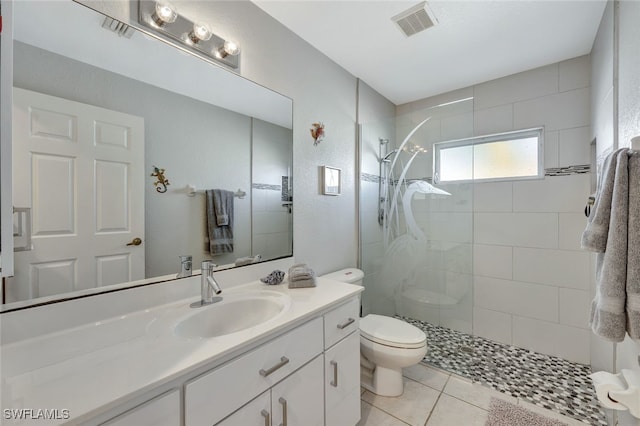 bathroom featuring vanity, toilet, tile patterned flooring, and a tile shower