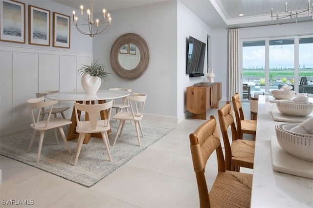 tiled dining room with baseboards, a chandelier, and a decorative wall