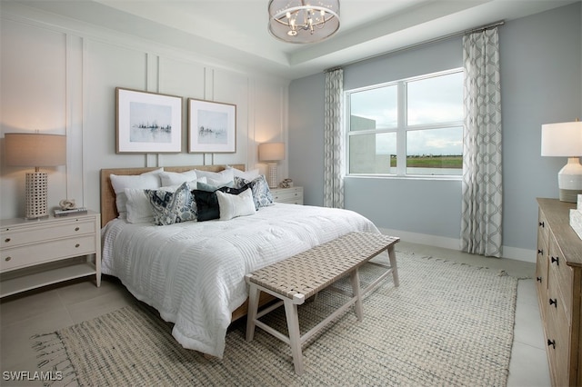 bedroom with light tile patterned floors, baseboards, a tray ceiling, and a notable chandelier