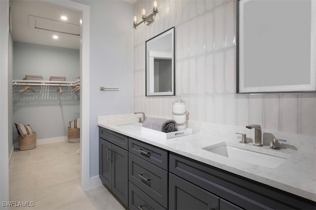 full bath featuring a walk in closet, tile patterned flooring, a sink, and double vanity