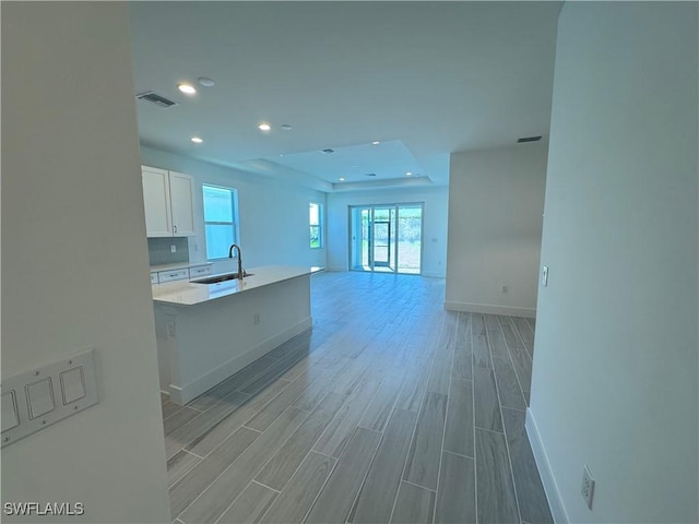 kitchen featuring visible vents, light wood-type flooring, white cabinetry, a sink, and recessed lighting