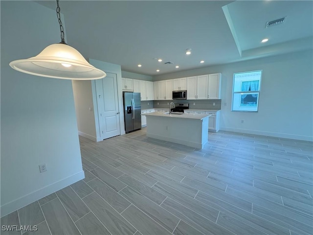 kitchen featuring visible vents, white cabinets, light countertops, appliances with stainless steel finishes, and a center island with sink