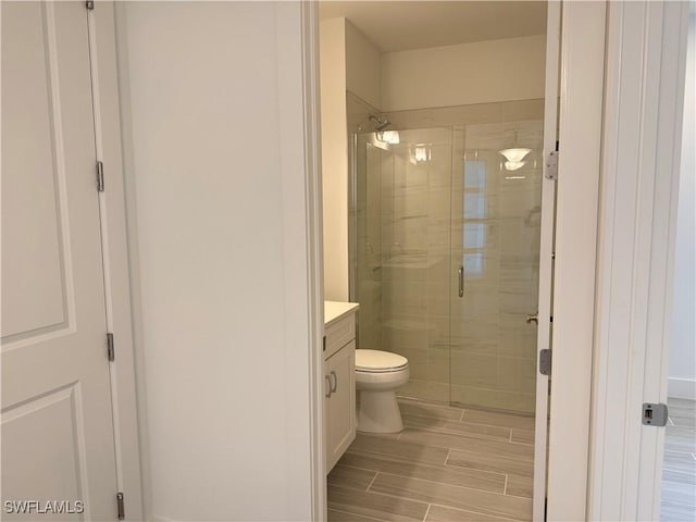 bathroom with toilet, a shower stall, and vanity