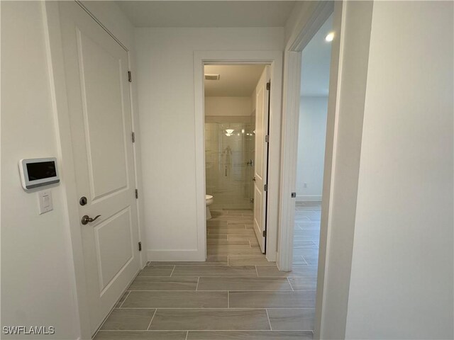 corridor with wood finish floors, visible vents, and baseboards