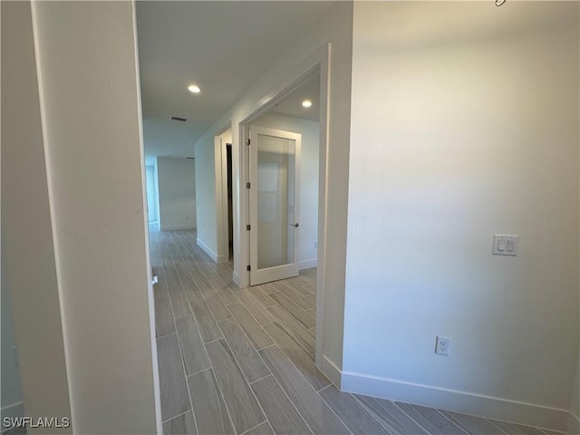 hallway with wood tiled floor, visible vents, baseboards, and recessed lighting