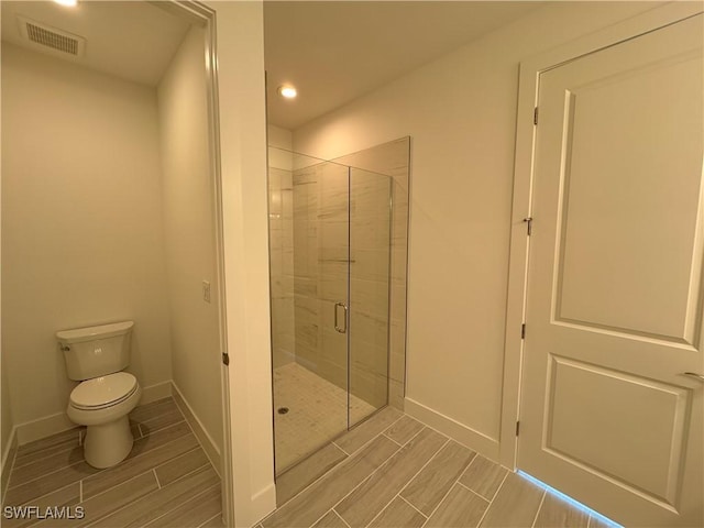 full bath featuring visible vents, toilet, a stall shower, wood tiled floor, and baseboards