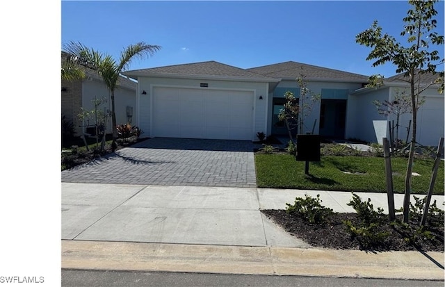 ranch-style home featuring decorative driveway and an attached garage