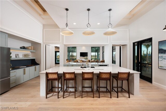 kitchen featuring hanging light fixtures, a breakfast bar, freestanding refrigerator, and light wood-style floors