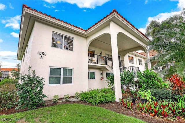 exterior space with stairway, stucco siding, and a tile roof