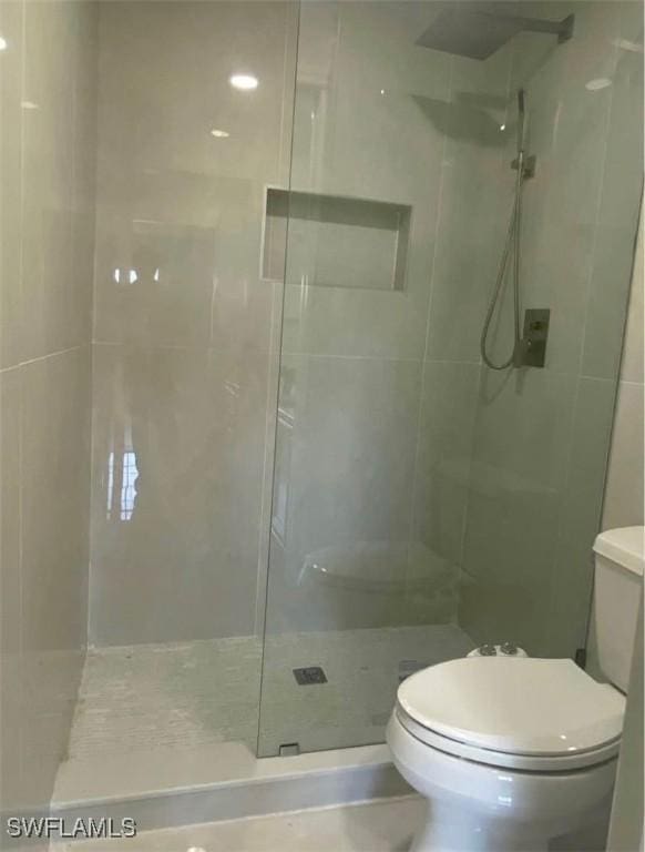 bathroom with tiled shower and toilet