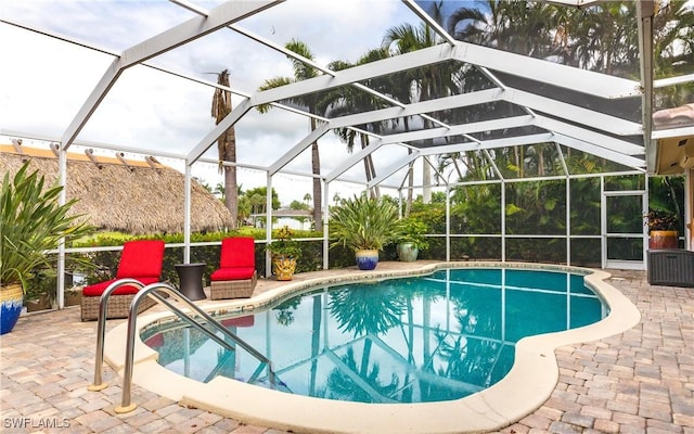 view of pool with glass enclosure and a patio area