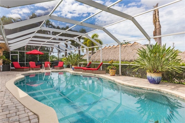 view of pool with glass enclosure and a patio area