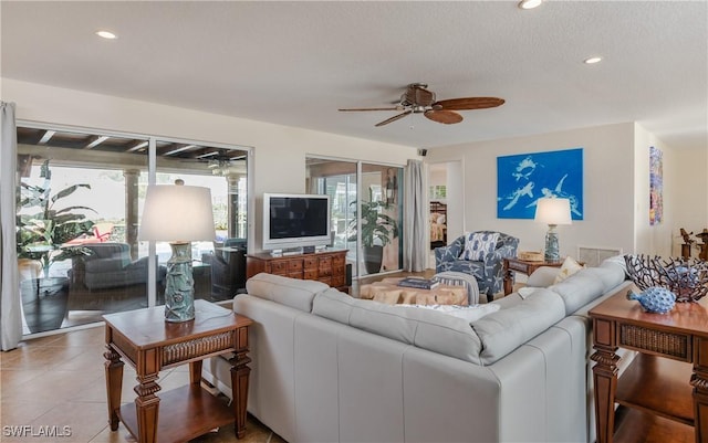 living room with ceiling fan, light tile patterned floors, and a textured ceiling