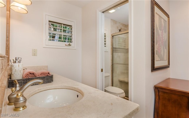 bathroom featuring vanity, a shower with shower door, and toilet