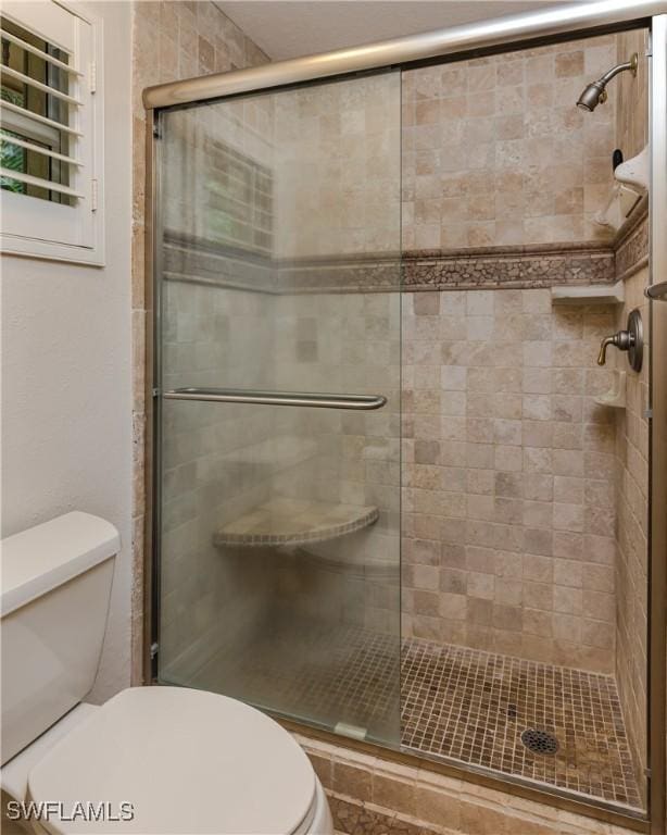 bathroom with a shower with door and toilet