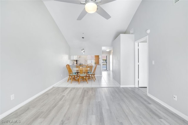 unfurnished dining area featuring ceiling fan, high vaulted ceiling, and light wood-type flooring