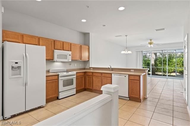 kitchen featuring kitchen peninsula, white appliances, ceiling fan with notable chandelier, hanging light fixtures, and light tile patterned flooring