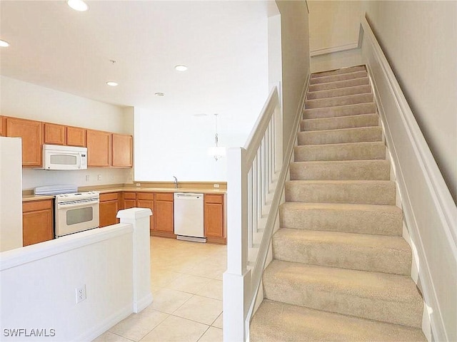 kitchen featuring pendant lighting, white appliances, sink, and light tile patterned floors