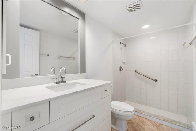 bathroom with a tile shower, vanity, and toilet