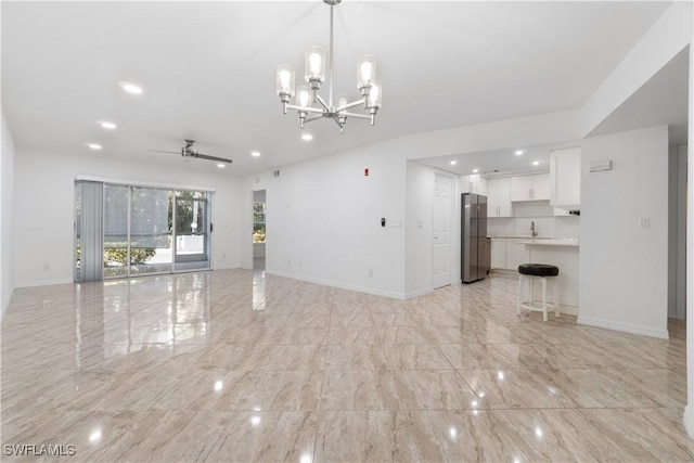 unfurnished living room with sink and ceiling fan with notable chandelier