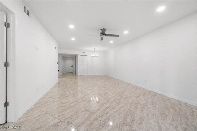 empty room featuring ceiling fan with notable chandelier