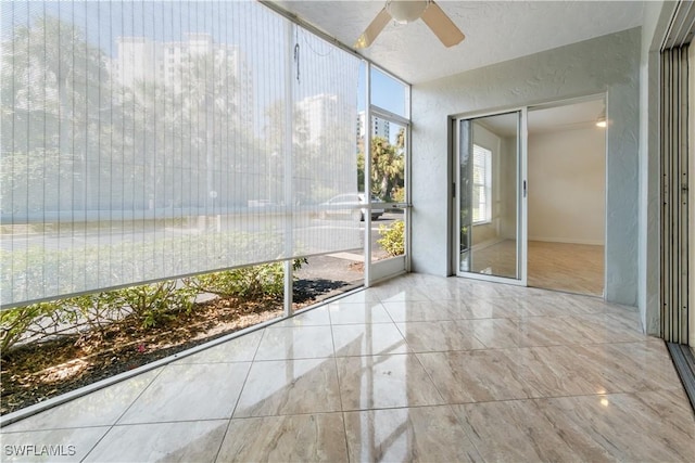 unfurnished sunroom featuring ceiling fan