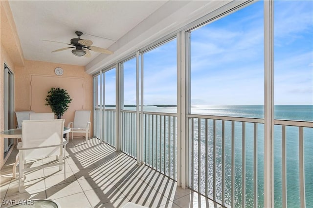 unfurnished sunroom with a water view and ceiling fan