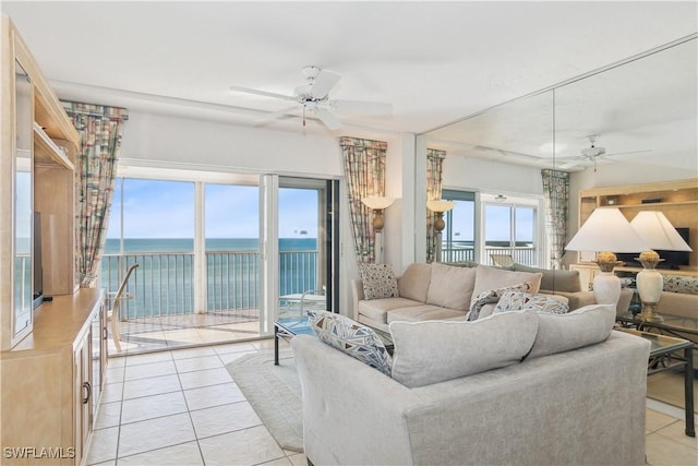 tiled living room with ceiling fan and a water view