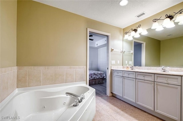 bathroom featuring tile patterned floors, a tub, vanity, and a textured ceiling