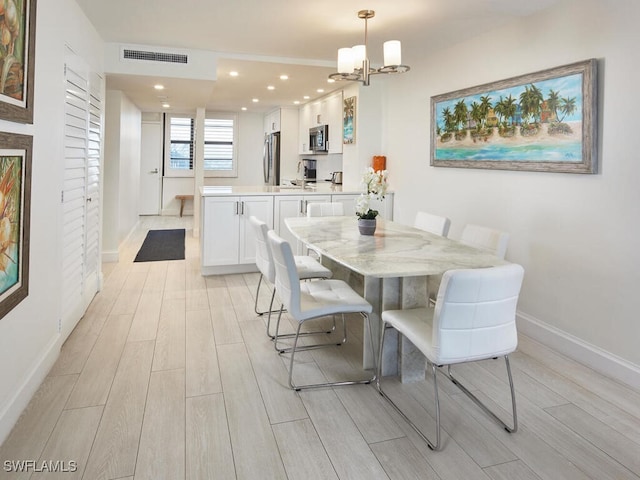 dining room with light hardwood / wood-style floors and a notable chandelier