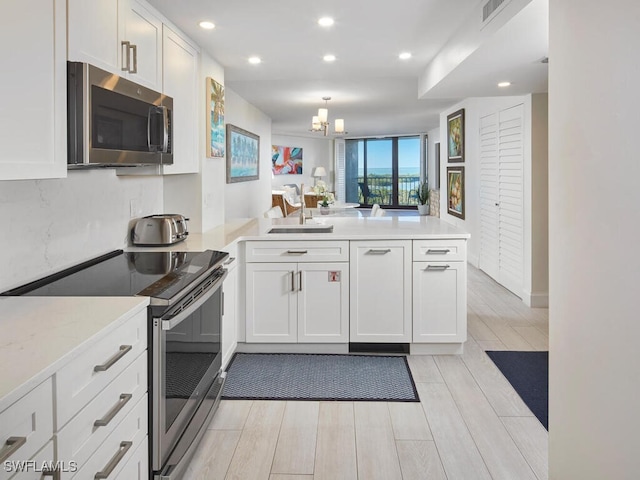 kitchen featuring white cabinetry, sink, stainless steel appliances, light hardwood / wood-style flooring, and kitchen peninsula